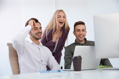 Photo of Group of colleagues laughing together in office