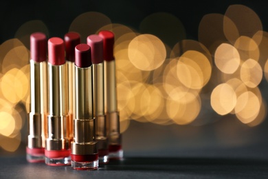 Set of bright lipsticks on table against blurred lights, space for text
