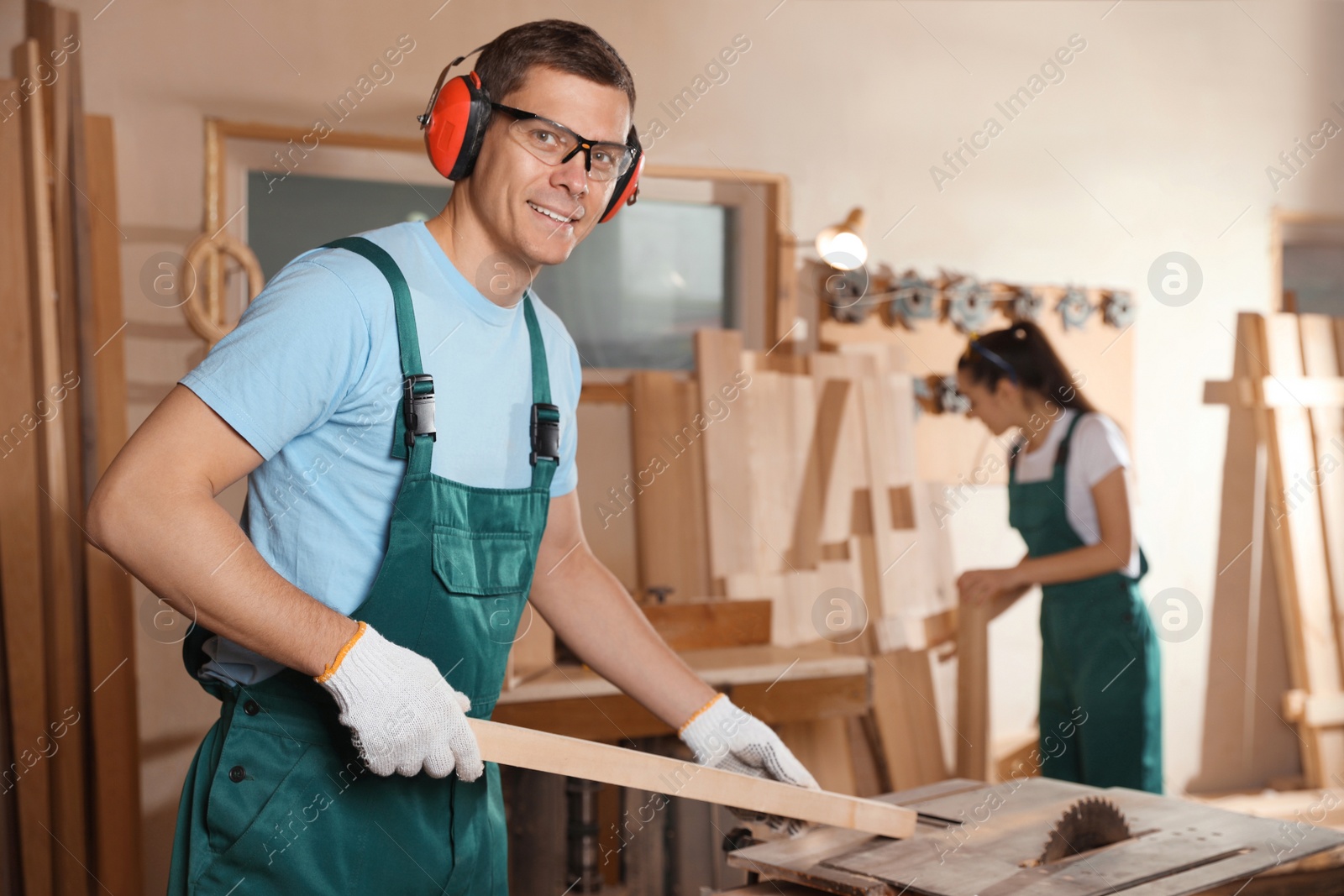 Photo of Professional carpenter with wooden plank in workshop