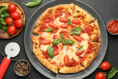 Delicious Margherita pizza, ingredients and cutter on black table, top view