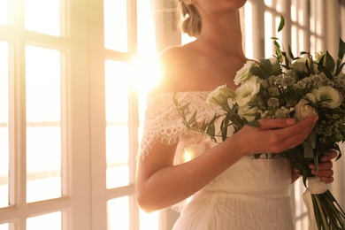 Photo of Bride in beautiful wedding dress with bouquet indoors, closeup