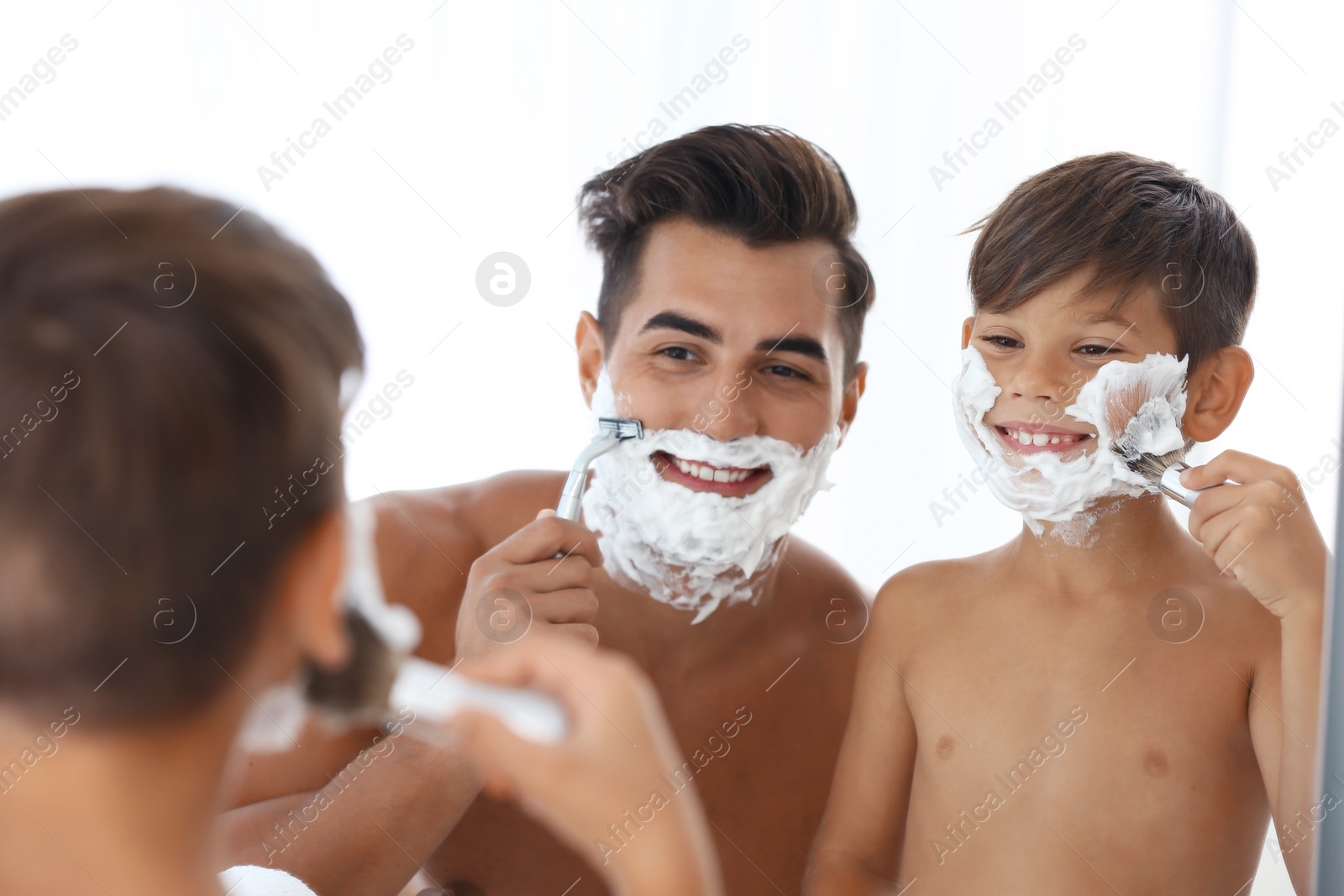 Photo of Father and son having fun while shaving in bathroom