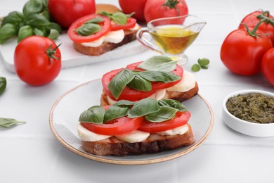 Photo of Delicious Caprese sandwiches with mozzarella, tomatoes, basil and pesto sauce on white table