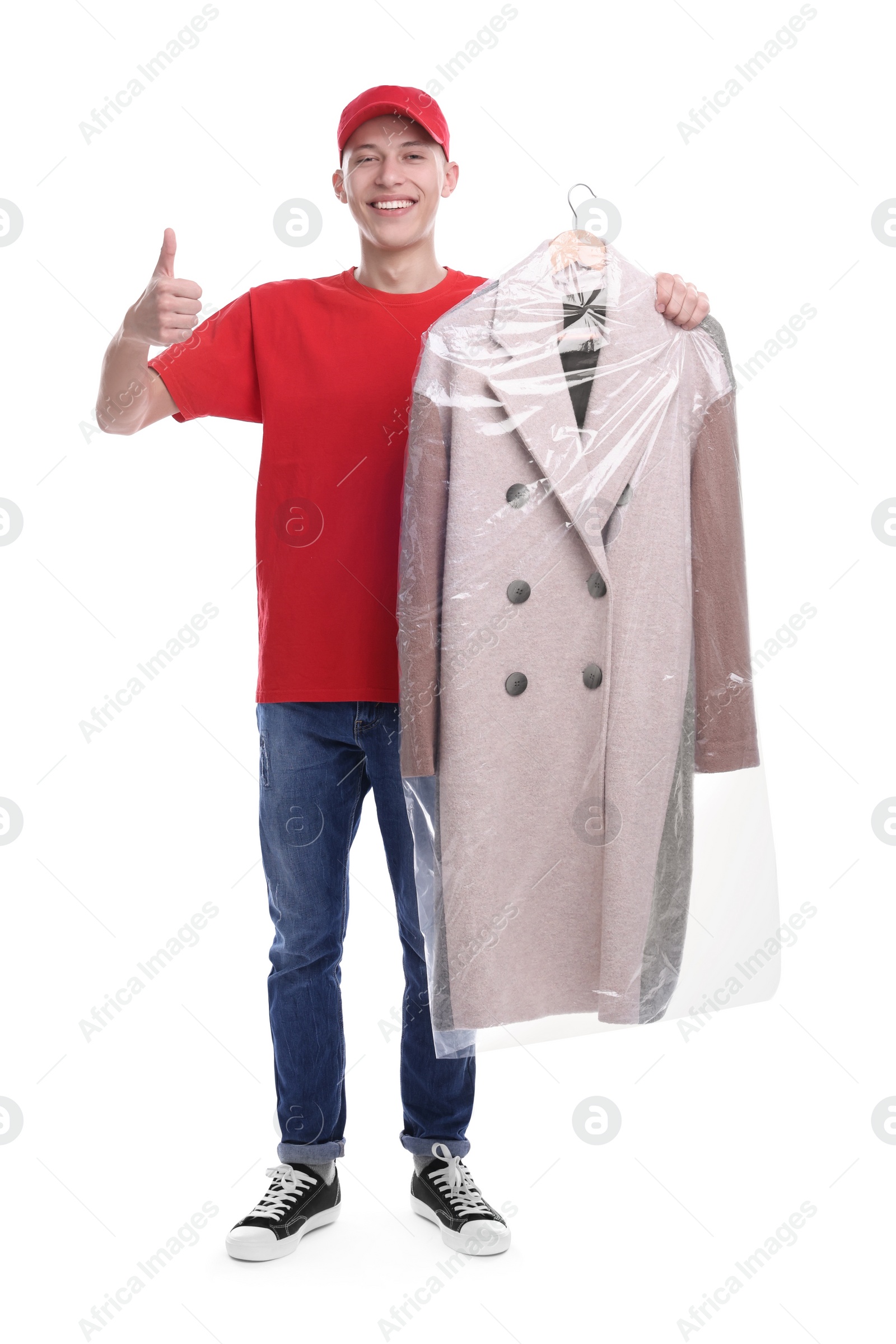 Photo of Dry-cleaning delivery. Happy courier holding coat in plastic bag and showing thumbs up on white background