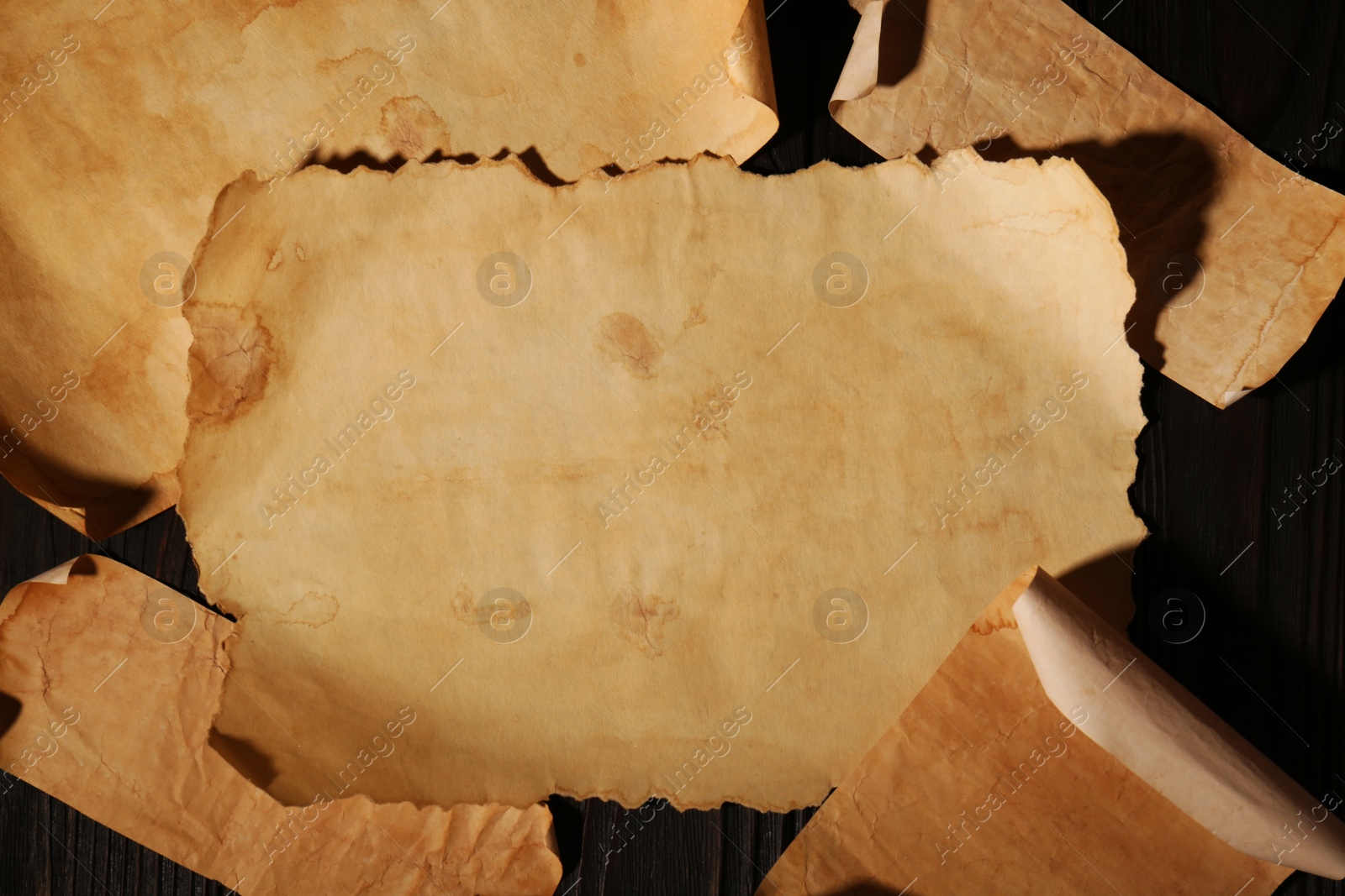 Photo of Sheets of old parchment paper on wooden table, flat lay