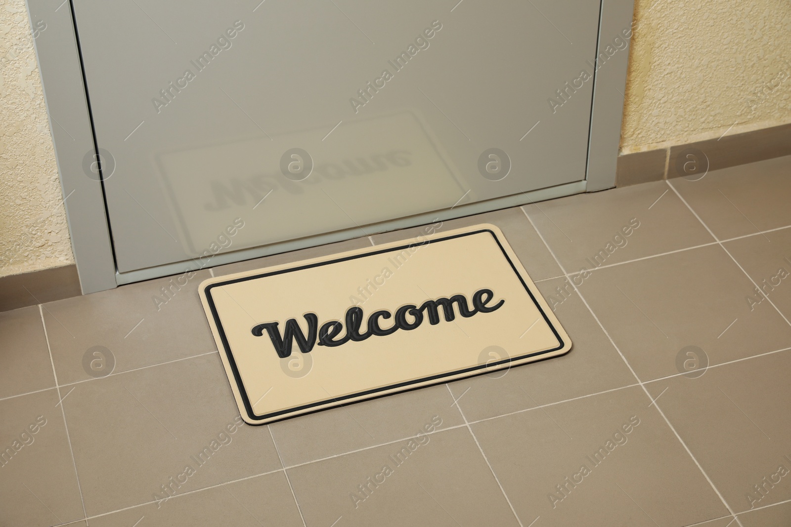 Photo of Beautiful beige doormat with word Welcome on floor near entrance