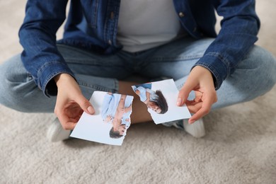 Photo of Woman holding torn photo on floor, closeup. Divorce concept