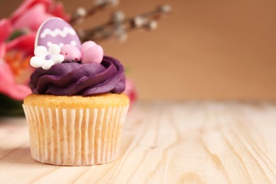 Photo of Tasty cupcake with Easter decor on wooden table, closeup. Space for text