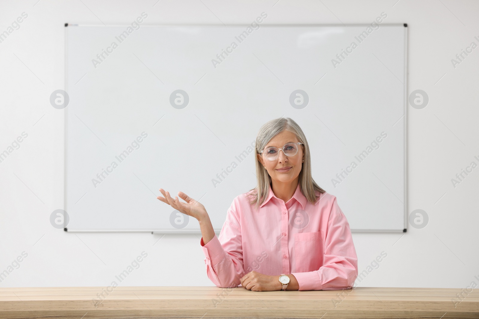 Photo of Professor giving lecture at desk in classroom, space for text