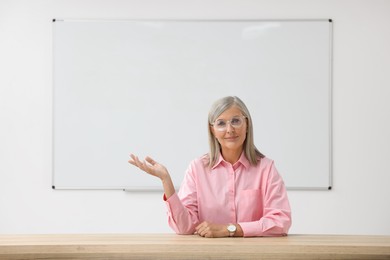 Photo of Professor giving lecture at desk in classroom, space for text