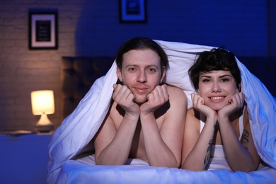 Photo of Lovely young couple on bed at night time