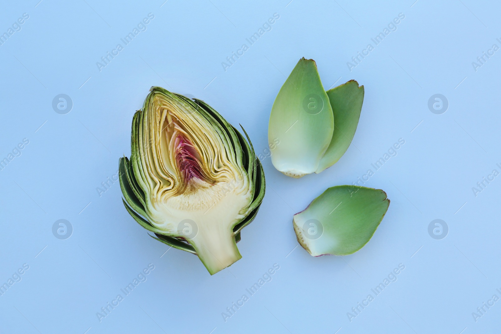 Photo of Half of fresh raw artichoke and leaves on white background, flat lay