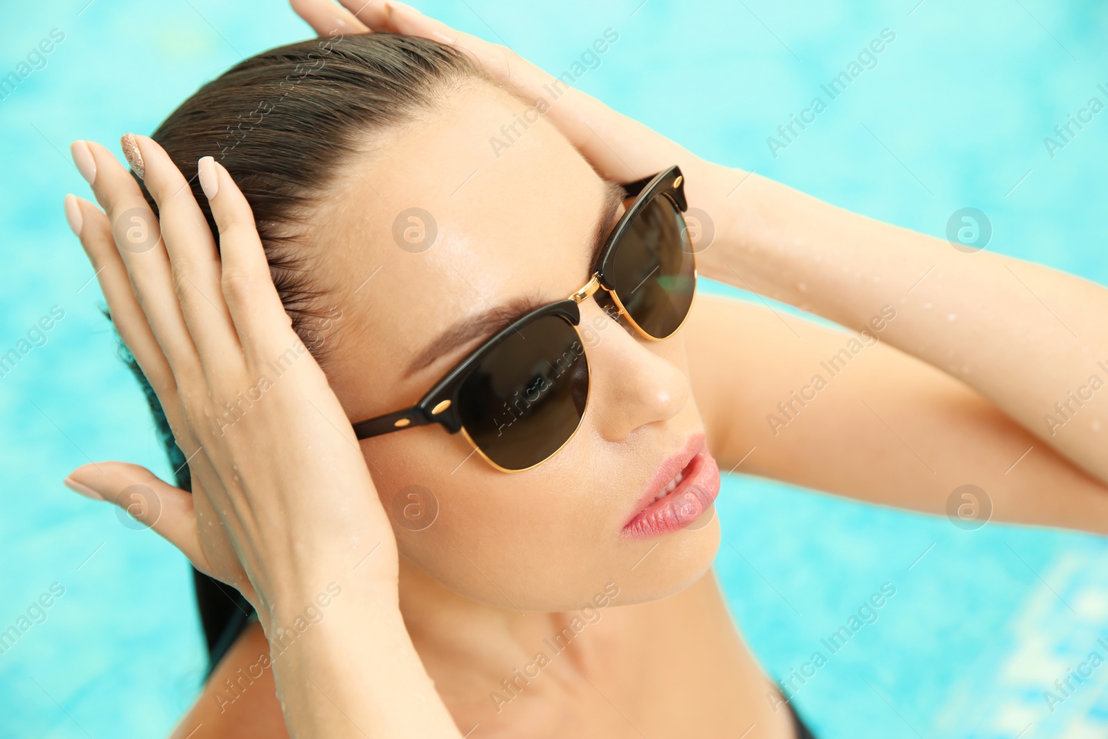 Photo of Portrait of beautiful young woman wearing sunglasses in swimming pool