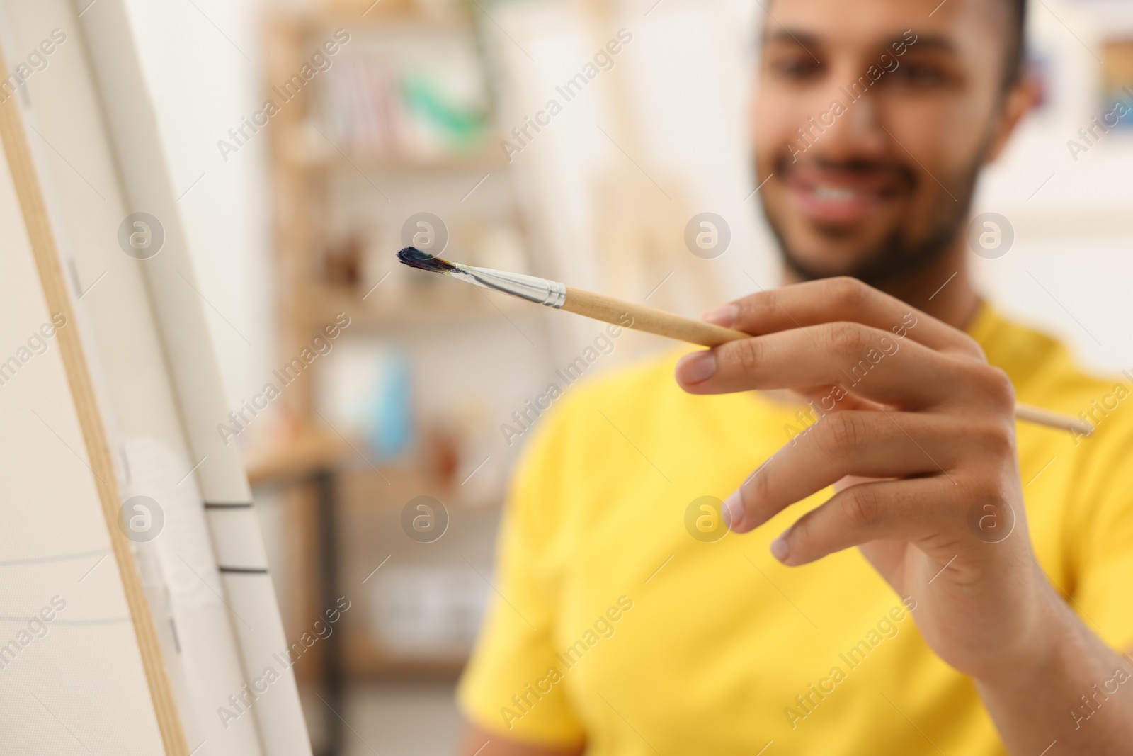 Photo of Young man painting in studio, selective focus. Creative hobby