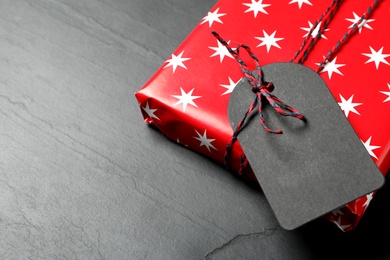 Wrapped present with blank tag on black background, closeup. Space for text
