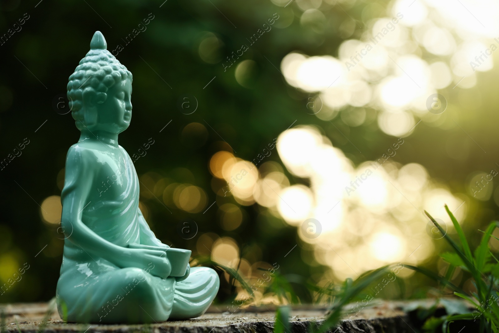 Photo of Decorative Buddha statue on stump outdoors, space for text