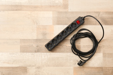 Extension cord on wooden floor, top view with space for text. Electrician's equipment