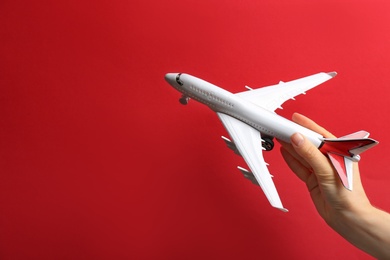 Woman holding toy airplane on red background, closeup. Space for text