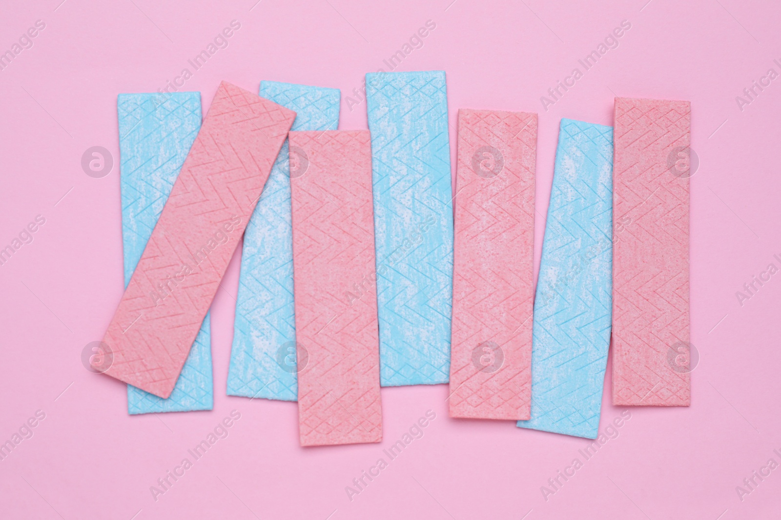 Photo of Sticks of tasty chewing gum on pink background, flat lay