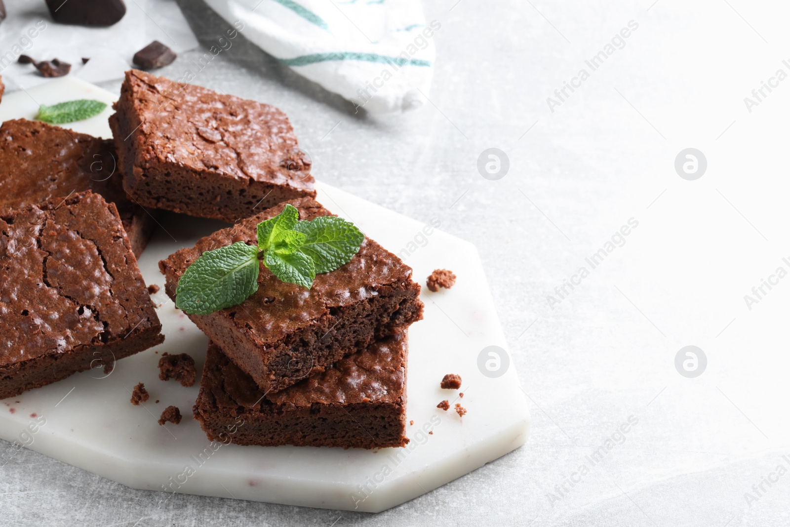 Photo of Delicious chocolate brownies with fresh mint on grey table. Space for text