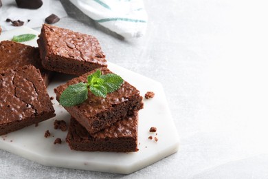 Delicious chocolate brownies with fresh mint on grey table. Space for text