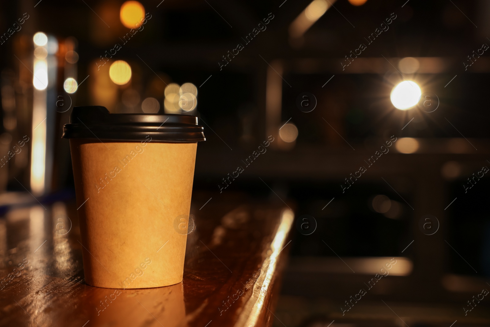 Photo of Paper coffee cup on wooden table in cafe. Space for text