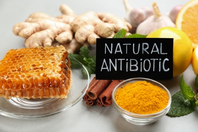 Different fresh products and card with phrase Natural Antibiotic on grey table, closeup