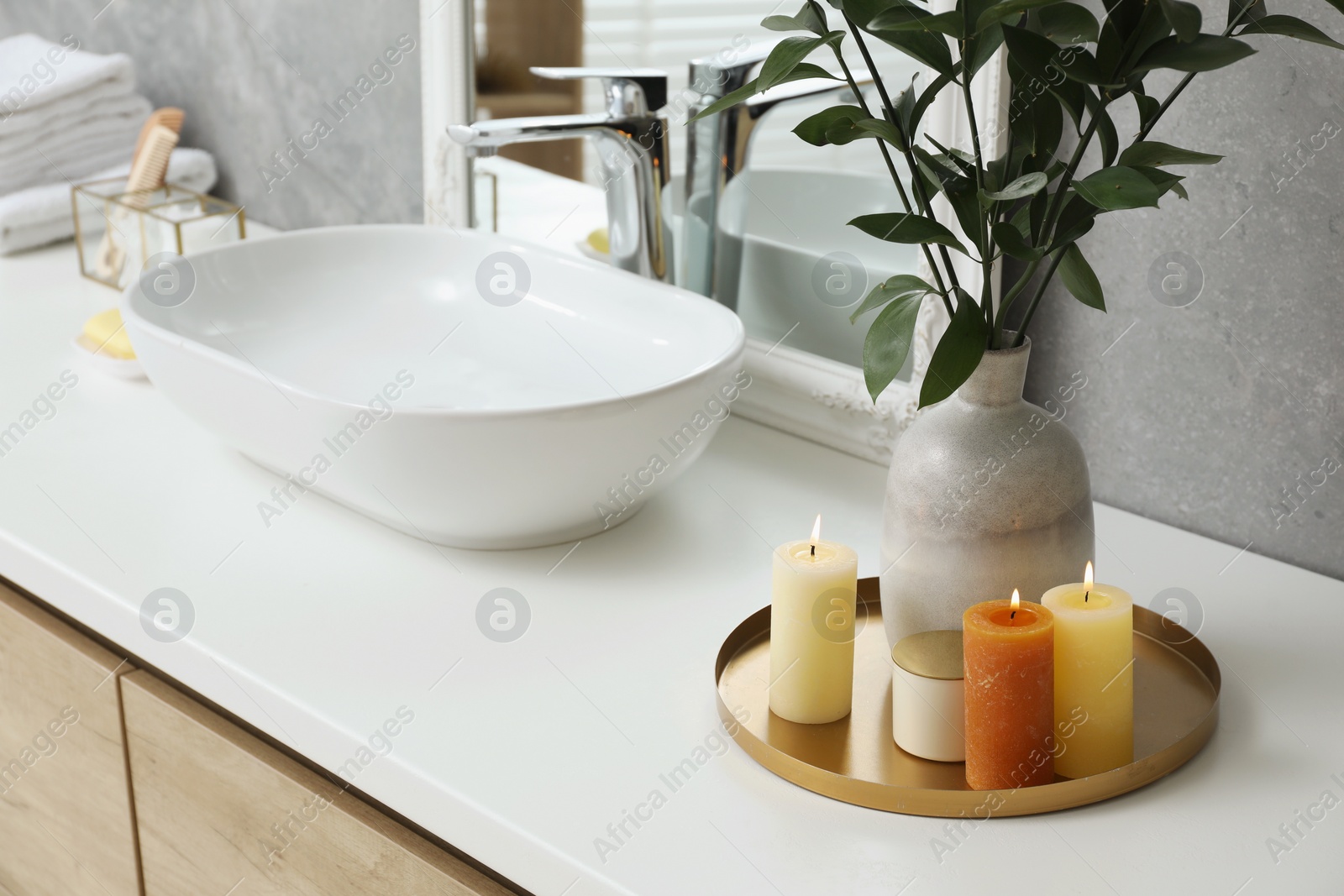 Photo of Beautiful plant in vase and burning candles near vessel sink and mirror on bathroom vanity