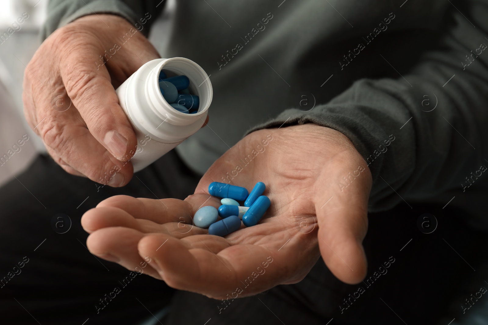 Photo of Senior man pouring pills from bottle into hand, closeup