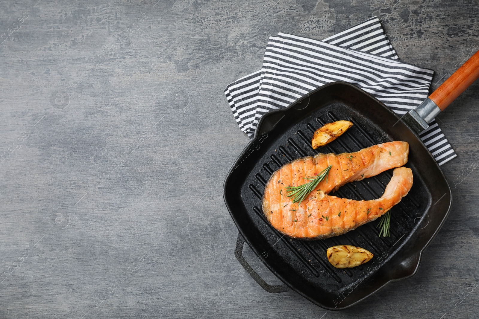 Photo of Frying pan with tasty salmon steak on grey background