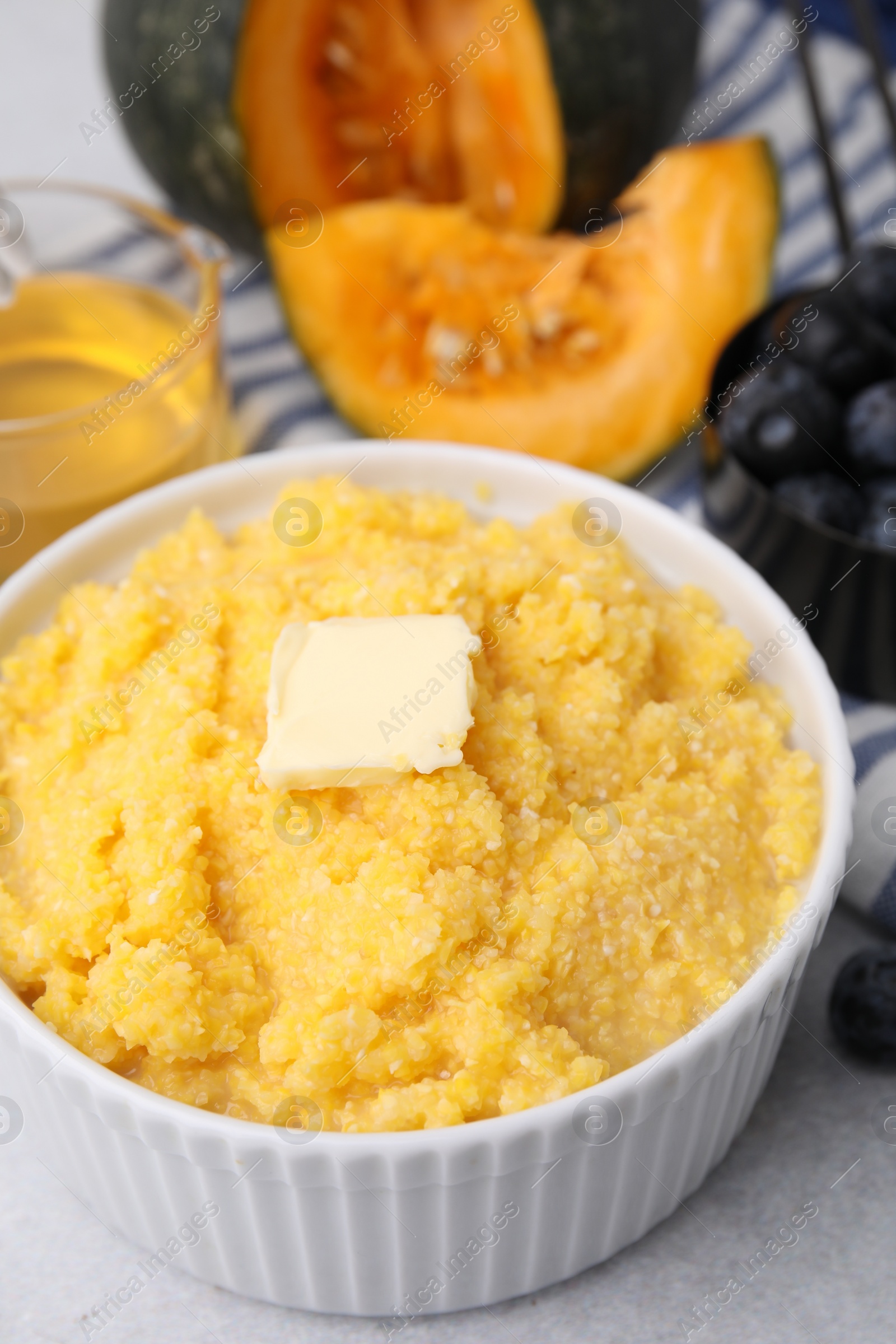 Photo of Tasty cornmeal with butter in bowl on table, closeup