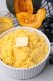 Photo of Tasty cornmeal with butter in bowl on table, closeup