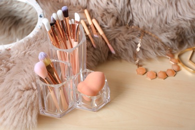 Photo of Organizer with set of professional makeup brushes and accessories on wooden table. Space for text