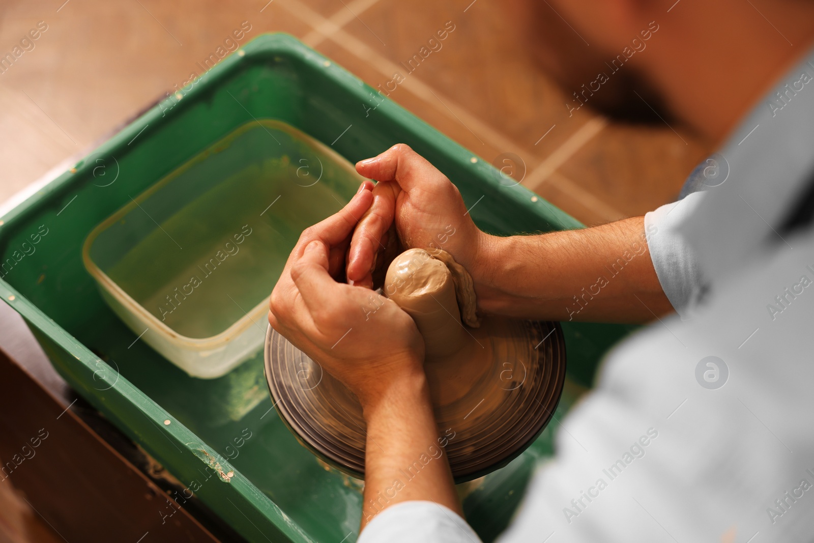 Photo of Man crafting with clay on potter's wheel, closeup