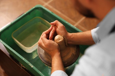 Man crafting with clay on potter's wheel, closeup