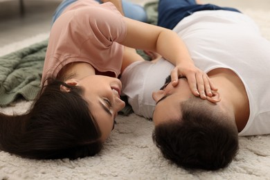 Affectionate young couple spending time together on soft carpet at home