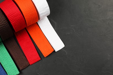 Photo of Colorful karate belts on gray background, flat lay. Space for text