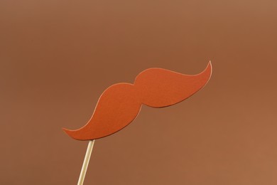 Photo of Fake paper mustache party prop on light brown background