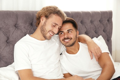 Happy gay couple on bed at home