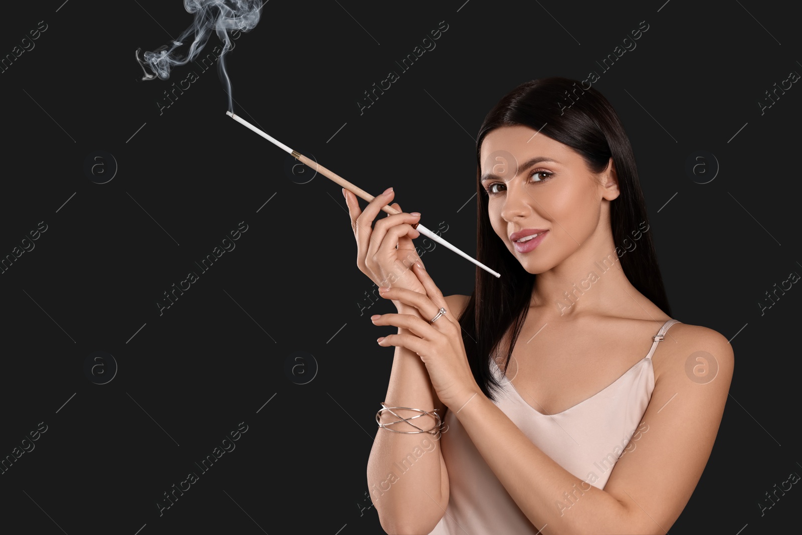 Photo of Woman using long cigarette holder for smoking on black background, space for text