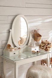 Photo of Wooden dressing table with decorative elements and makeup products in room. Interior design