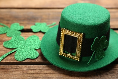 Photo of Leprechaun hat and decorative clover leaves on wooden table, closeup. St Patrick's Day celebration