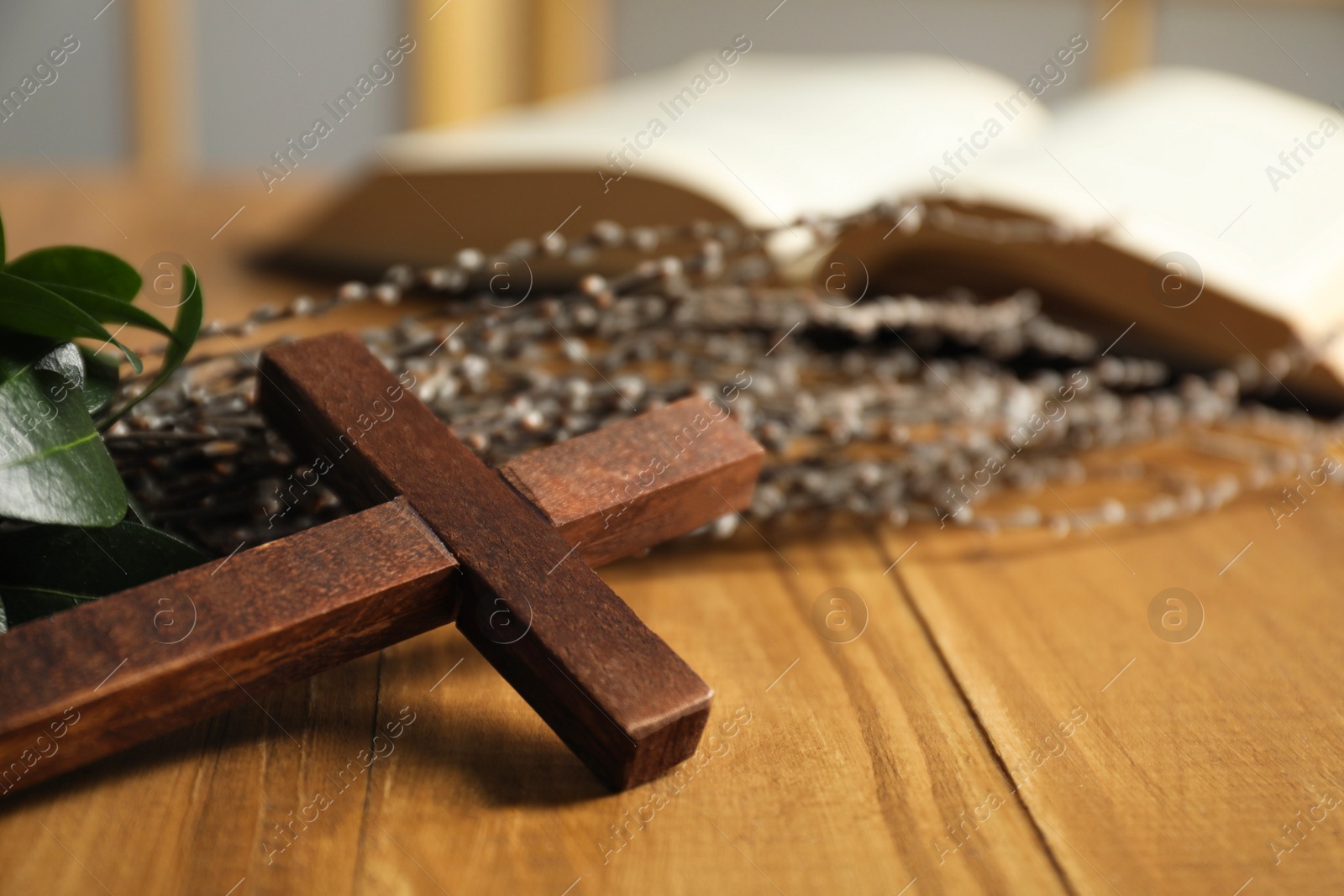 Photo of Cross and willow branches on wooden table, closeup