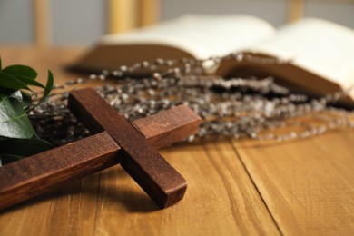 Photo of Cross and willow branches on wooden table, closeup