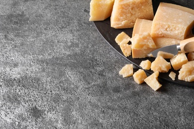 Photo of Parmesan cheese with board and knife on grey table. top view. Space for text