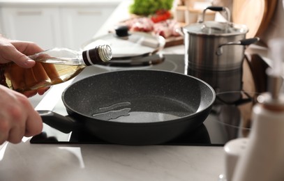 Photo of Man pouring cooking oil into frying pan in kitchen, closeup