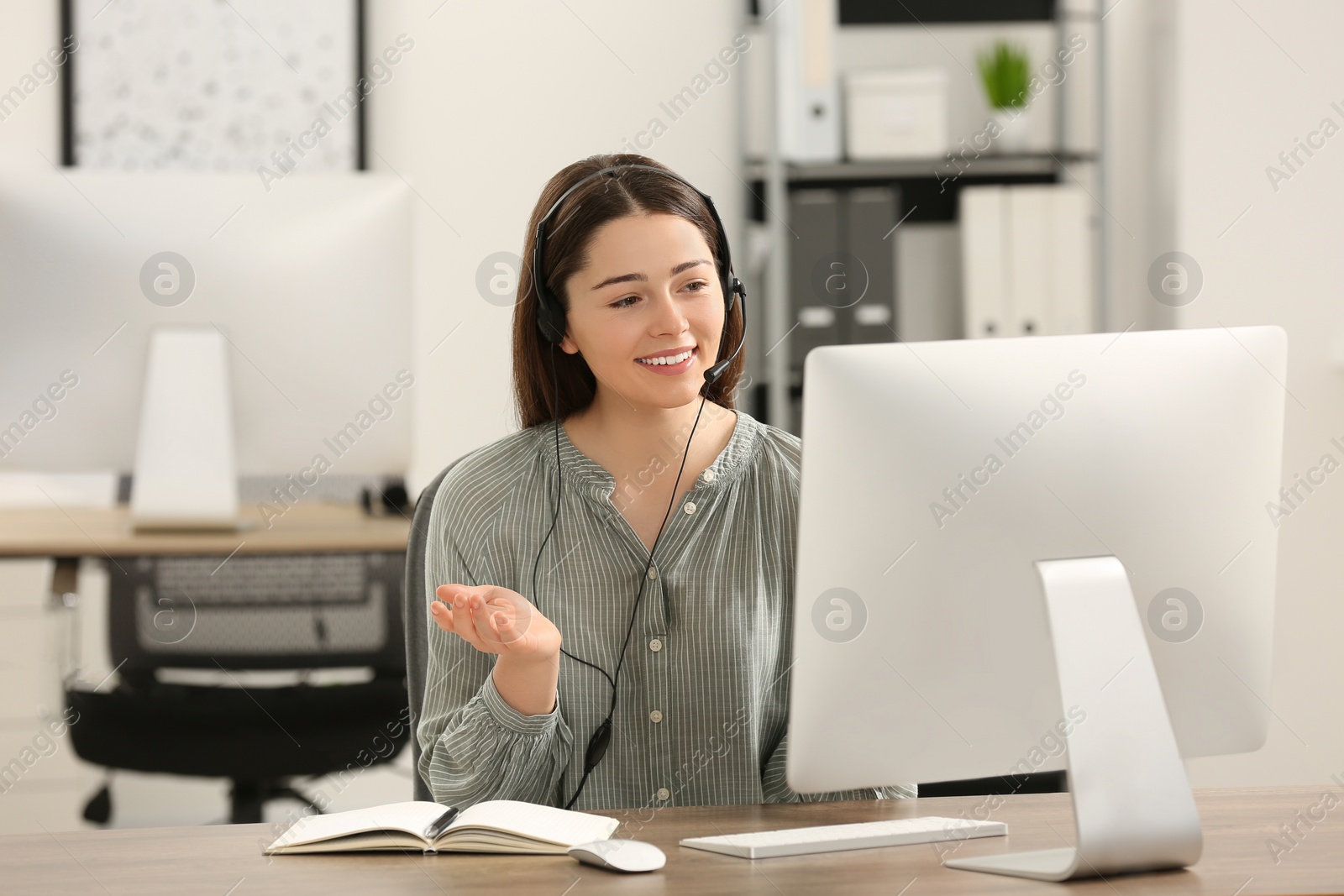 Photo of Hotline operator with headset working on computer in office