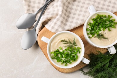 Photo of Bowls with tasty creamy soup of parsnip served on light grey table, flat lay