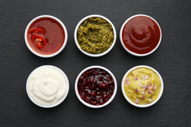 Photo of Different tasty sauces in bowls on black table, flat lay