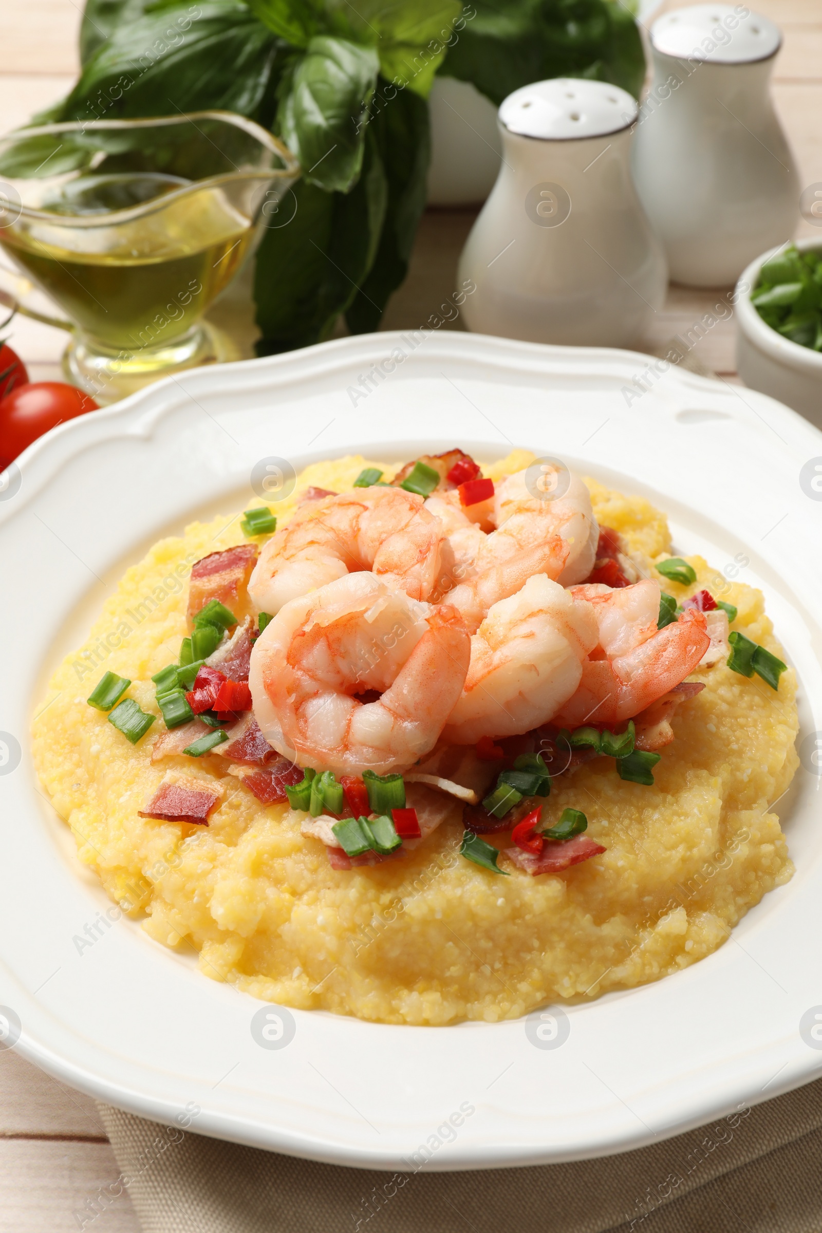 Photo of Plate with fresh tasty shrimps, bacon, grits, green onion and pepper on table, closeup